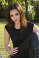 A woman sitting on the ground in a black shirt and black pants.