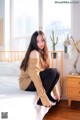 A woman sitting on a bed in a bedroom.