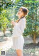 A woman in a white dress standing in front of a tree.