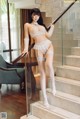 A woman in a white lingerie posing on a staircase.