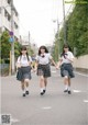 three girls in school uniforms walking down the street