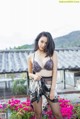 A woman in lingerie posing on a balcony with flowers.