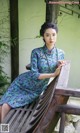 A woman in a blue dress sitting on a wooden bench.