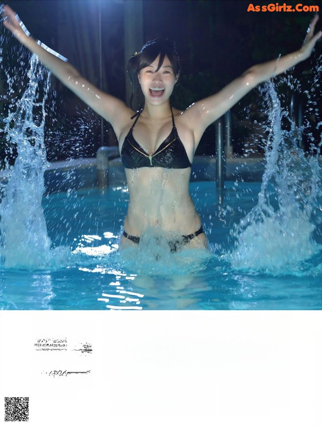 A woman in a black bikini standing in a pool.